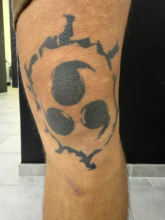 Sharingan aus Naruto mit Flammen, Anime Tattoo auf dem Knie, verheilt
