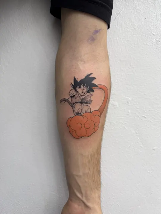 Son Goku als Kind mit Wolke, farbiges Anime Tattoo auf der Wade