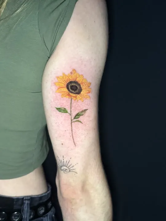 Sonnenblume, farbiges Tattoo auf dem Oberarm