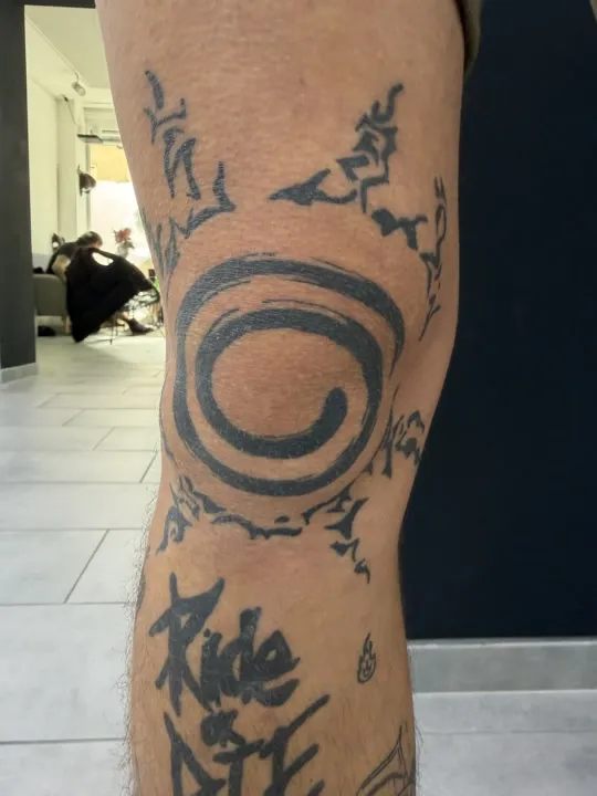 Spirale mit Flammen und Schriftzug Ride or Die, Tattoo auf dem Knie, verheilt